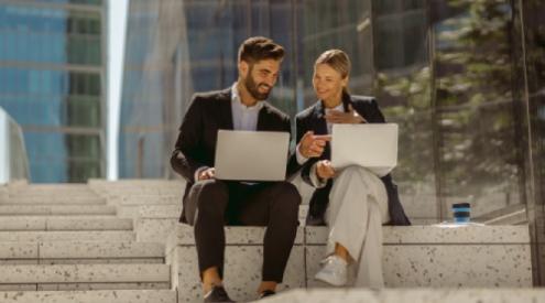 a man and woman looking at laptops